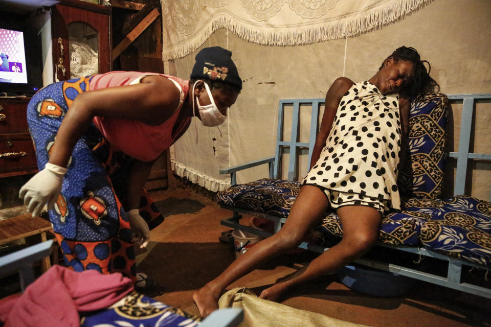 Traditional birth attendant Emily Owino, left, prepares to help Veronica Atieno, right, deliver her baby in Emily's one-room house during a dusk-to-dawn curfew, late at night in the Kibera slum of Nairobi, Kenya Thursday, May 28, 2020. Kenya already had one of the worst maternal mortality rates in the world, and though data are not yet available on the effects of the curfew aimed at curbing the spread of the coronavirus, experts believe the number of women and babies who die in childbirth has increased significantly since it was imposed mid-March. (AP Photo/Brian Inganga)