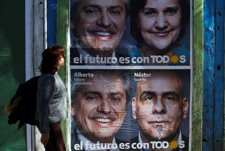 A pedestrian walks by a campaign poster for opposition presidential candidate Alberto Fernandez, in Buenos Aires