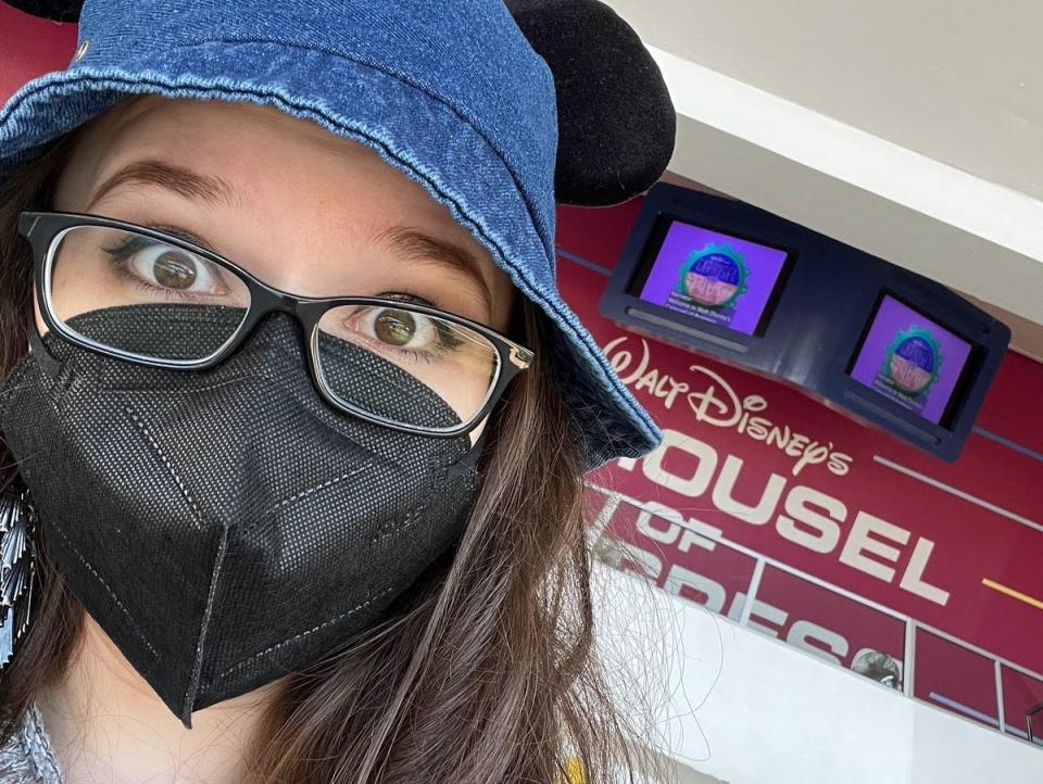 sofia posing in front of the carousel of progress wearing a jean mickey hat