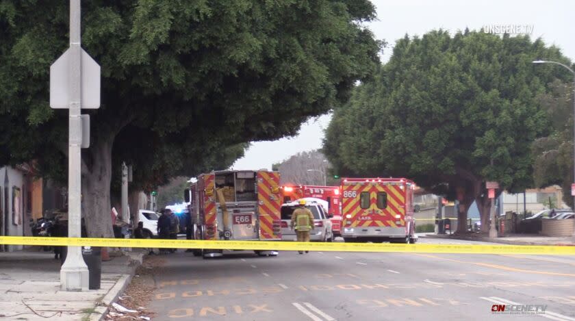 Firetrucks and ambulances around an SUV on a street behind crime scene tape