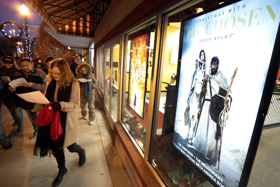 A poster for "Christmas with the Chosen: Holy Night" is seen outside of a movie theater as a group of immigration organization supporters sing carols during a Posada celebration, Sunday, Dec. 17, 2023, in Fort Morgan, Colo. Organizers put on the Posada, a Latin-American tradition based on the religious events of Joseph and Mary searching for shelter before the birth of Jesus, as a way for migrants in Colorado to feel a sense of unity during the holiday season. (AP Photo/Julio Cortez)