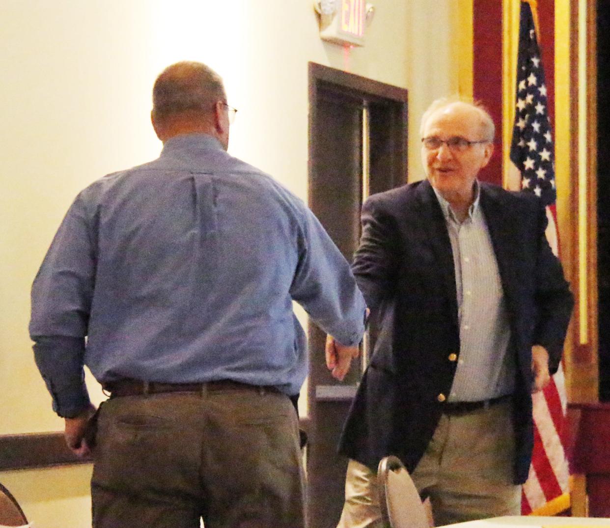 Current Pontiac City Administrator Bob Karls, right, congratulates his replacement, Jim Woolford, at Monday's city council meeting.