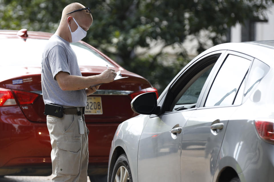 A member of the Mississippi Health Response Team takes down medical information from a person potentially affected by a COVID-19 incidence at the Mississippi Legislature at the Capitol in Jackson, Miss., Monday, July 6, 2020. House Speaker Philip Gunn confirmed Sunday that he had recently tested positive for COVID-19. A makeshift drive-thru testing center was set in place on Capitol grounds. (AP Photo/Rogelio V. Solis)