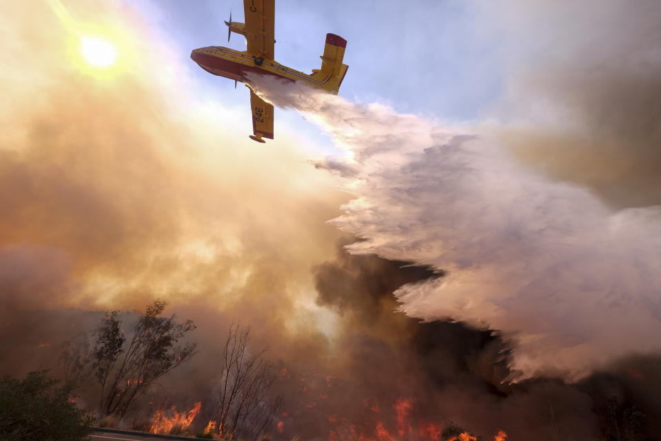 An air tanker drops water on a fire along the Ronald Reagan (118) Freeway in Simi Valley, California. Source: AP