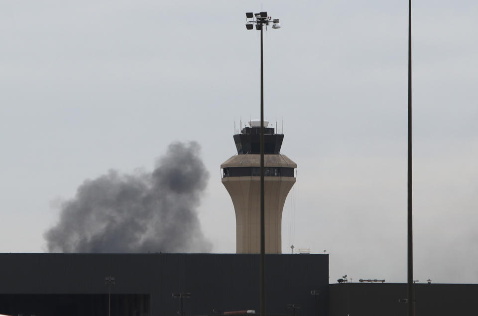 Smoke rises behind an air traffic control tower on west side of Dallas/Fort Worth International Airport in Grapevine, Dallas, Wednesday, Feb. 13, 2019. Flights at Dallas' two major airports were temporarily halted after air traffic controllers were forced to evacuate a building because of smoke, and the resulting flight delays are expected to continue for hours. (AP Photo/LM Otero)