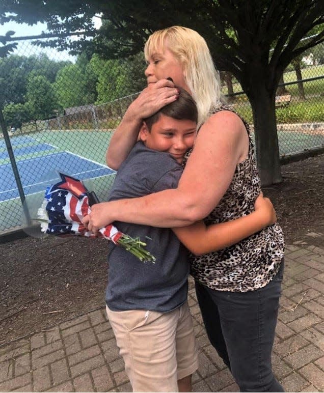 Kimberly Greenlee hugs Kolton Conrad in Rising Park after he returned her brother's dog tag. Conrad found the tag in the Hocking River on July 4, and with the help of his mother, was able to connect with Greenlee to give her the tag, 46 years after her brother's death.