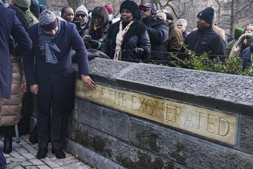 Raymond Santana Jr., left, one of five men exonerated after being wrongfully convicted as teenagers for the 1989 rape of a jogger in Central Park, moves his hand over the words "Gate of the Exonerated" during a naming ceremony for the northeast gateway of Central Park, Monday, Dec. 19, 2022, in New York. The entrance was named to honor Santana, Kevin Richardson, Yusef Salaam, Antron McCray, Korey Wise — the five men exonerated in the case. (AP Photo/Bebeto Matthews)