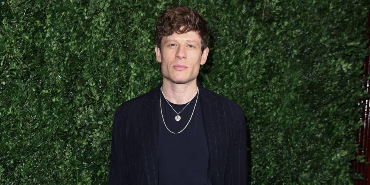 james norton wears a black suit and black top accessorised with two golden neck chains