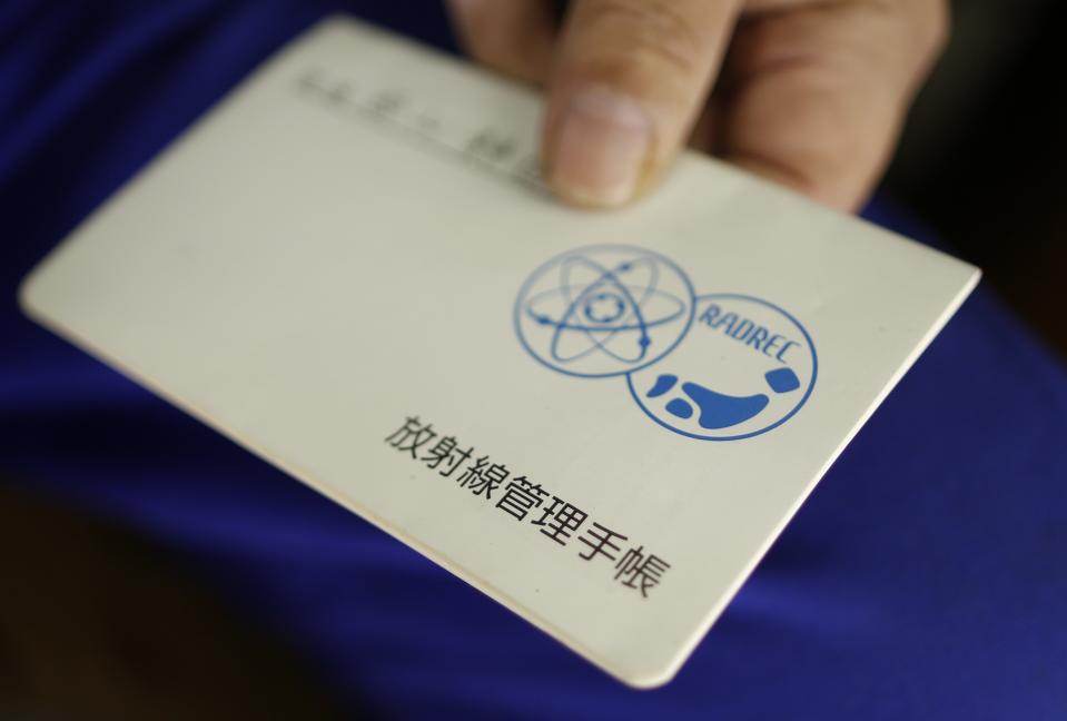 Shizuya Nishiyama from Hokkaido shows a notebook for radioactive exposure management for workers involved in the clean up of areas affected by the Fukushima nuclear disaster at Sendai Station