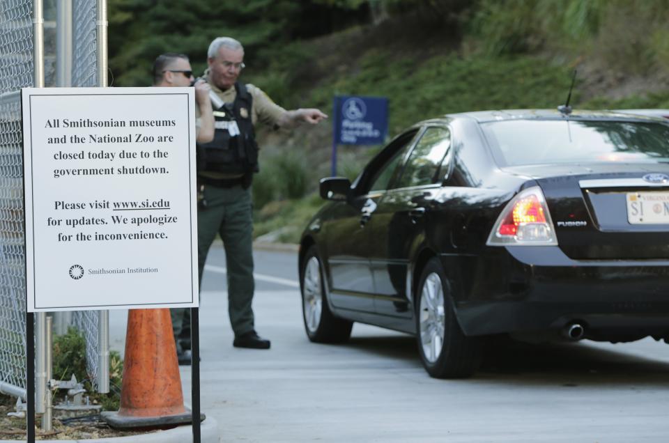 Security personnel (L) check identification from a driver attempting to enter the Smithsonian National Zoo in Washington October 2, 2013. The zoo is one of the many popular public attractions closed due to the U.S. government shutdown, which is now into day number two. REUTERS/Gary Cameron (UNITED STATES - Tags: POLITICS BUSINESS TRAVEL)