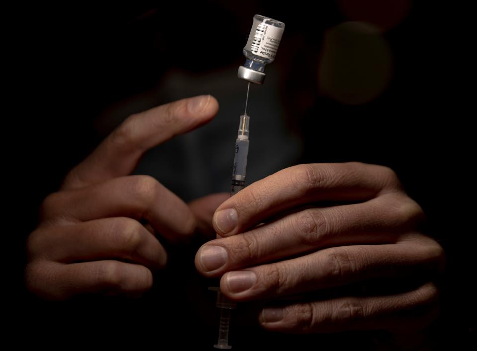 Army National Guard Sgt. Noah Thomas taps bubble out of a syringe of the Pfizer-BioNTech Covid-19 vaccine in 2021 at the Salem Health Covid-19 vaccination clinic. A new round of vaccines should be available in Oregon this month.