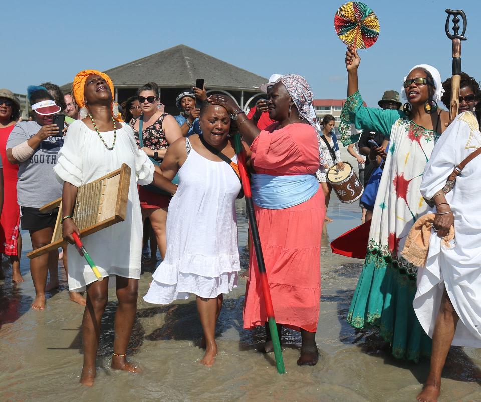 Patt Gunn places a scoop of water on Lila Womack's head as they stand in the edge of the ocean on June 19, 2022 during the Tybee Juneteenth Wade In. Womack made the drive from Atlanta to participate in the event for the first time and was overcome by emotion as she made her way into the water.