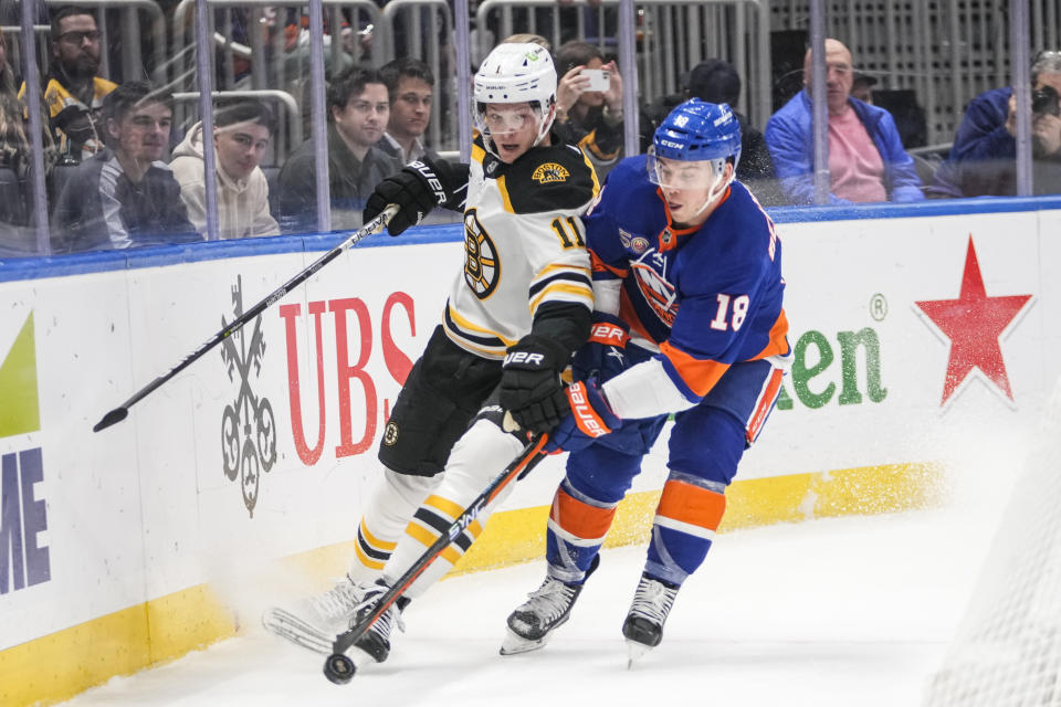 Boston Bruins' Trent Frederic (11) fights for control of the puck with New York Islanders' Anthony Beauvillier (18) during the first period of an NHL hockey game Wednesday, Jan. 18, 2023, in Elmont, N.Y. (AP Photo/Frank Franklin II)