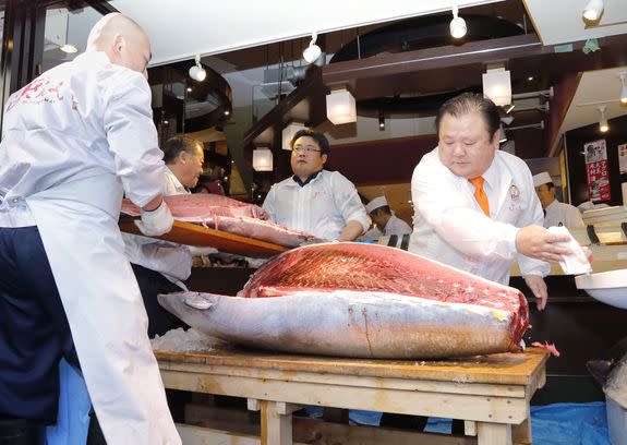 Kiyoshi Kimura, right, cuts a 212-kilogram bluefin tuna at his main sushi restaurant in Tokyo on Jan. 5, 2017.