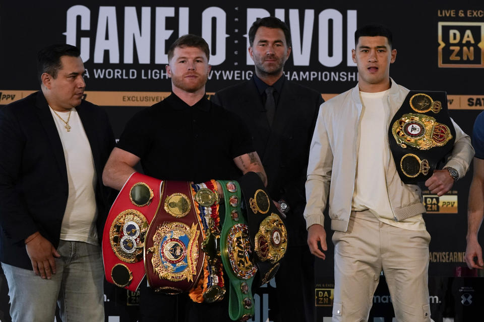 Canelo Álvarez, segundo desde la izquierda, de México, posa con Dmitry Bivol, derecha, de Rusia, el miércoles 2 de marzo de 2022 en San Diego mientras el promotor Eddie Hearn, segundo desde la derecha, y el entrenador de Álvarez, Eddy Reynoso, izquierda, observan .  Álvarez tiene programado pelear contra Bivol en un combate de boxeo en Las Vegas el 7 de mayo. (AP Photo/Gregory Bull)