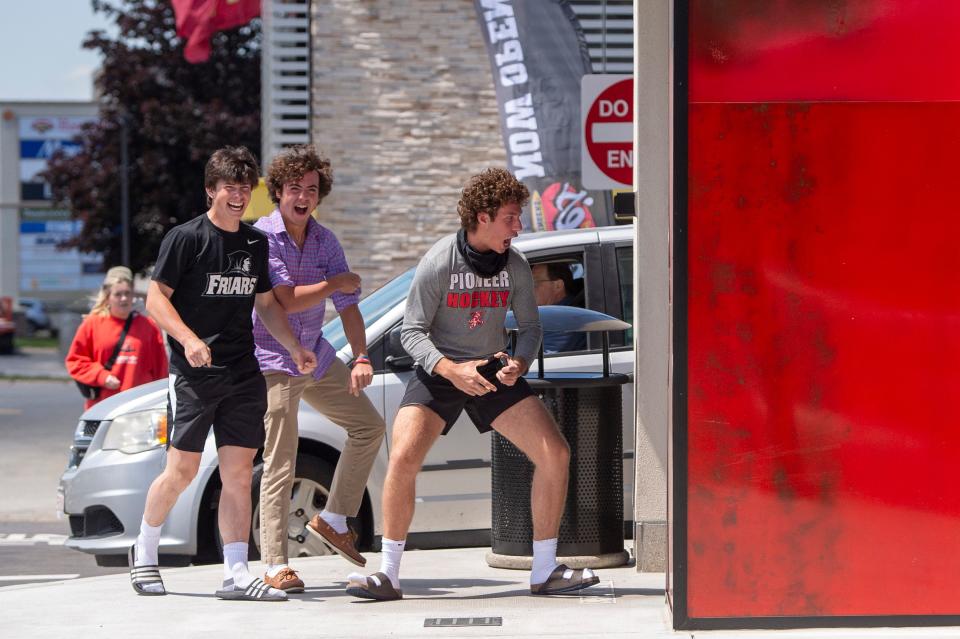 Jack Beauregard, Chris Pompei and Sean Farrell, all seniors at St. John's High School in Shrewsbury, show their excitement as they enter Raising Cane's Chicken Fingers on Boston Post Road West in Marlborough, May 17, 2023.