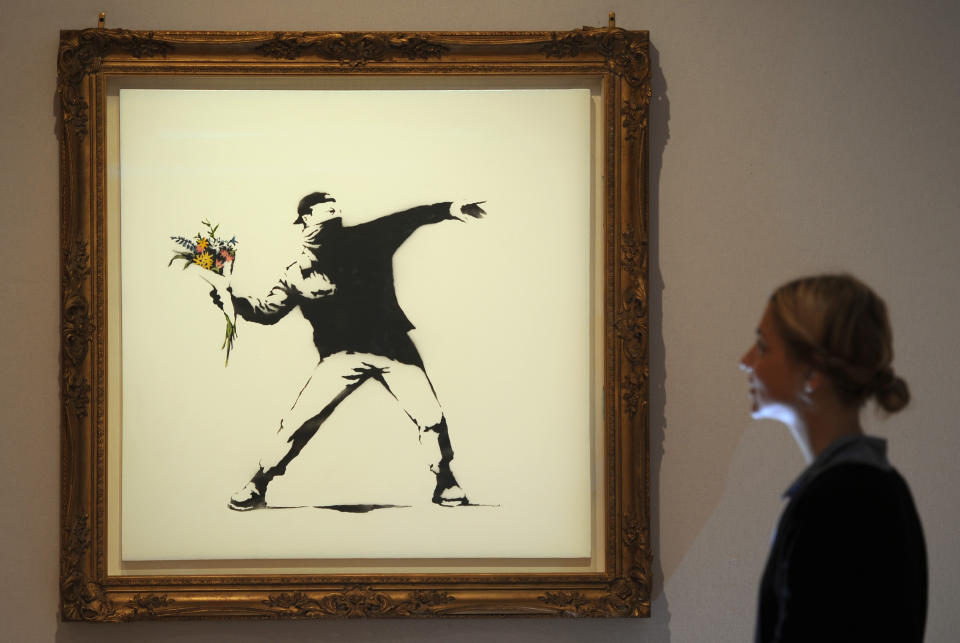 Bonhams assistant Bernice Robaglia views Banksy's 'Love is in the Air' which is expected to fetch 100,000 at auction on the 27th of June at Bonhams in London.   (Photo by Anthony Devlin/PA Images via Getty Images)