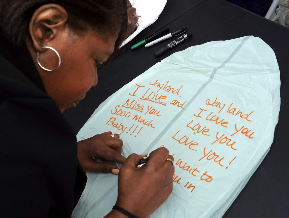 Pamela Walker writes a note to her late son Jayland, a 25-year-old man who was shot and killed by Akron police two years ago, before a memorial held in his honor Thursday in Akron.