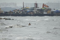 A resident swims along strong waves as Typhoon Noru approaches the seaside slum district of Tondo in Manila, Philippines, Sunday, Sept. 25, 2022. The powerful typhoon shifted and abruptly gained strength in an "explosive intensification" Sunday as it blew closer to the northeastern Philippines, prompting evacuations from high-risk villages and even the capital, which could be sideswiped by the storm, officials said. (AP Photo/Aaron Favila)