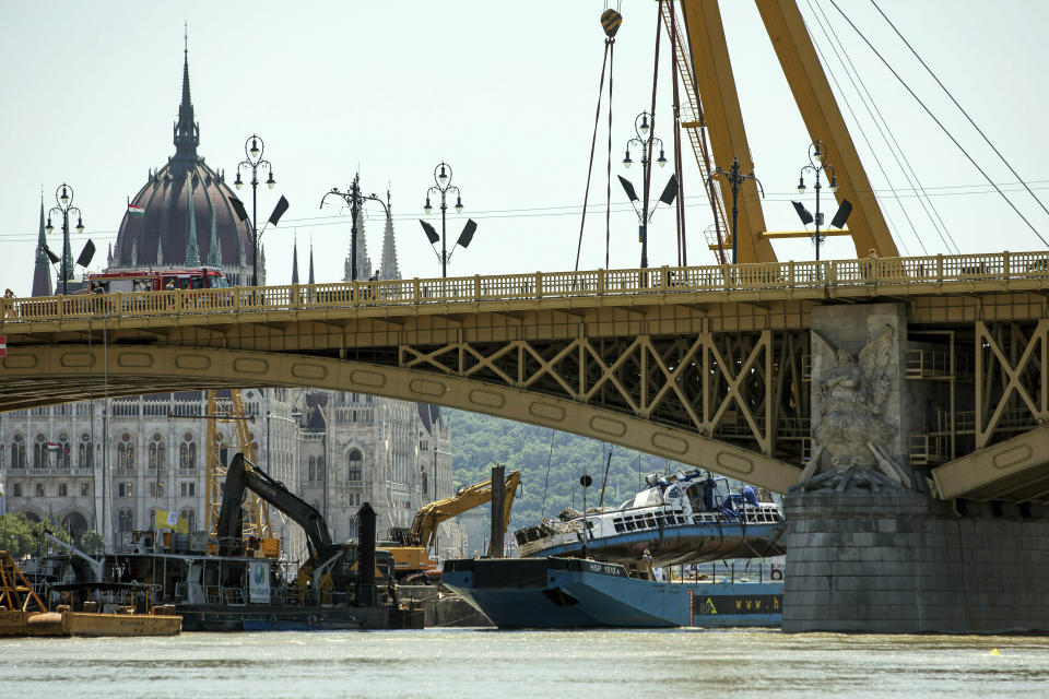 A crane places the wreckage of the sightseeing boat on a transporting barge at Margaret Bridge, the scene of the fatal boat accident in Budapest, Hungary, Tuesday, June 11, 2019. The Hableany sightseeing boat carrying 33 South Korean tourists and two Hungarian staff was crashed by a large river cruise ship and sank in the River Danube on May 29. Seven tourists survived, twenty people died, eight persons are still missing. (Balazs Mohai/MTI via AP)