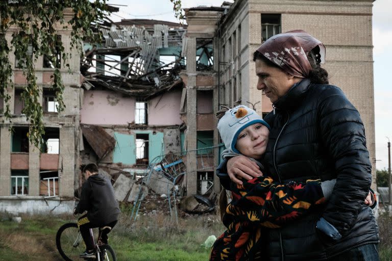 Olga Srednyakova de 51 años, madre soltera de ocho hijos, abraza a la hija menor, Vera, de 8 años, mientras otros cosechan hongos en un terreno abandonado de su escuela destruida en Konstantinovka, en la región de Donetsk, el 13 de octubre de 2022