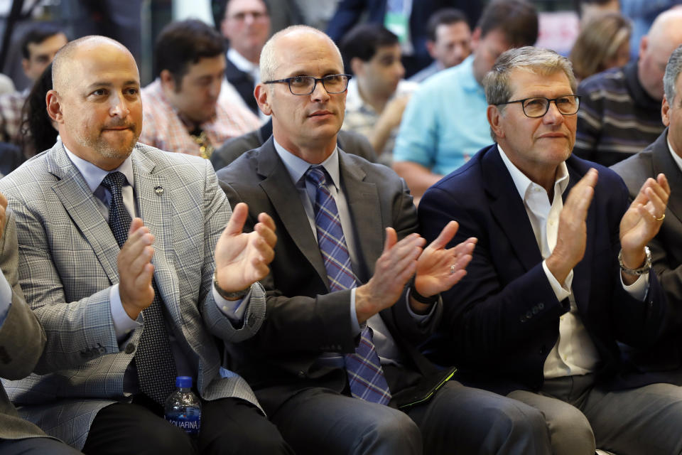UConn Director of Athletics David Benedict, left, men's basketball coach Dan Hurley, center, and women's basketball coach Geno Auriemma applaud during the announcement that the University of Connecticut is re-joining the Big East Conference, at New York's Madison Square Garden, Thursday, June 27, 2019. (AP Photo/Richard Drew)