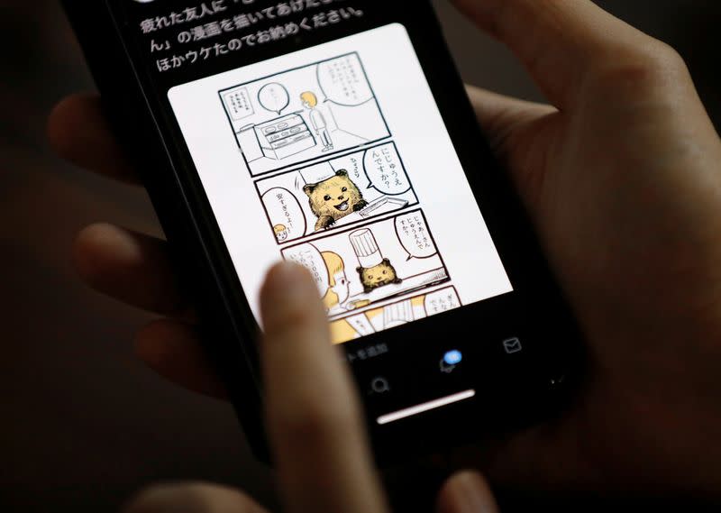 FILE PHOTO: Japanese manga artist Kamentotsu shows his his four-panel strip comic 'Koguma's Cake Shop' on his smartphone at his workspace in Tokyo