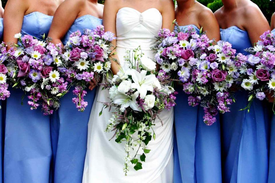 <p>Getty</p> A bride surrounded by her bridesmaids all holding bouquets