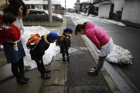 Children bow to greet their nursery school teacher (R) as they get into a school bus heading to the Emporium kindergarten in Koriyama, west of the tsunami-crippled Fukushima Daiichi nuclear power plant, Fukushima prefecture February 28, 2014. REUTERS/Toru Hanai