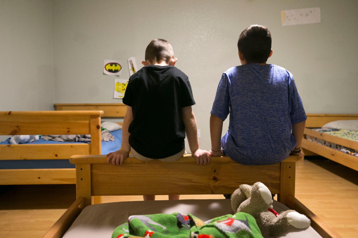 A second-grader (left) and a third-grader who are in the Arizona foster-care system sit on the edge of a bed in the sleeping area at the Child Crisis Arizona shelter in Mesa on Feb. 20, 2018.