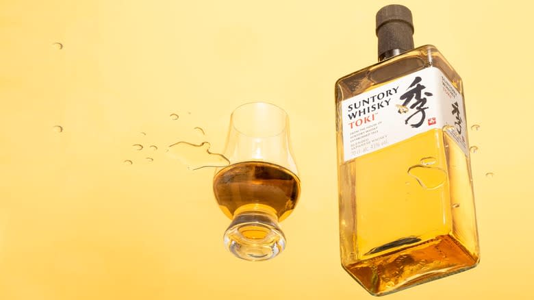 A bottle of Suntory Whisky Toki and glass on yellow background