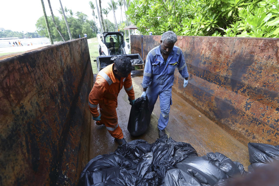 Workers load bags of oil-stained sands at Sentosa's Tanjong Beach area in Singapore, Sunday, June 16, 2024. An oil spill caused by a dredger boat hitting a stationary cargo tanker has blackened part of Singapore’s southern coastline, including the popular resort island of Sentosa, and sparked concerns it may threaten marine wildlife. (AP Photo/Suhaimi Abdullah)