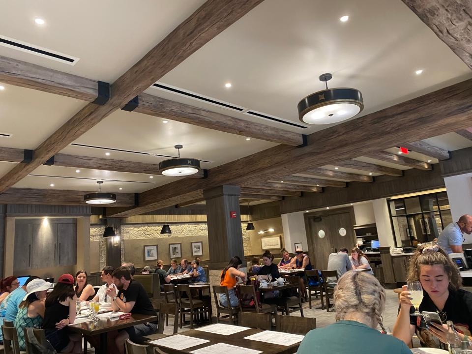 Interior view of Le Creperie de Paris at EPCOT with diners at tables and wooden beams on ceiling