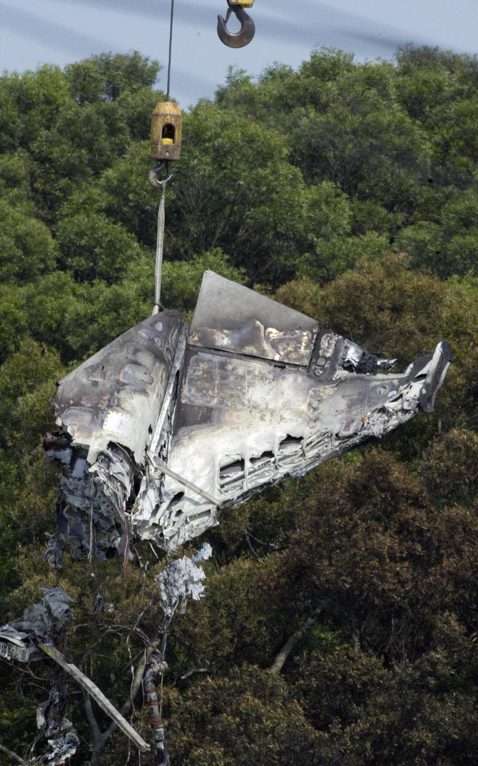 The wreckage of a crashed F-5F is lifted by a crane in Hsinchu, northern Taiwan, on May 11, 2007. Two Taiwanese fighter pilots and two Singaporean servicemen were killed when an F-5F jet crashed into a military compound during an exercise. <em>STR/AFP via Getty Images</em>