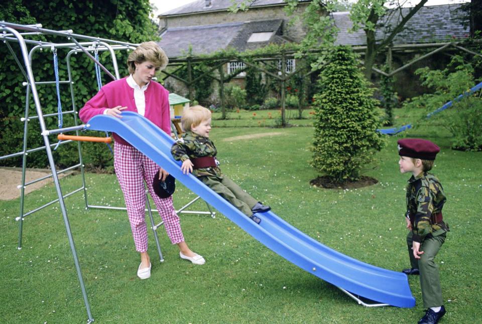 <p>The Princess of Wales plays with her sons, dressed in miniature Parachute Regiment uniforms, on a slide in the garden at Highgrove. </p>