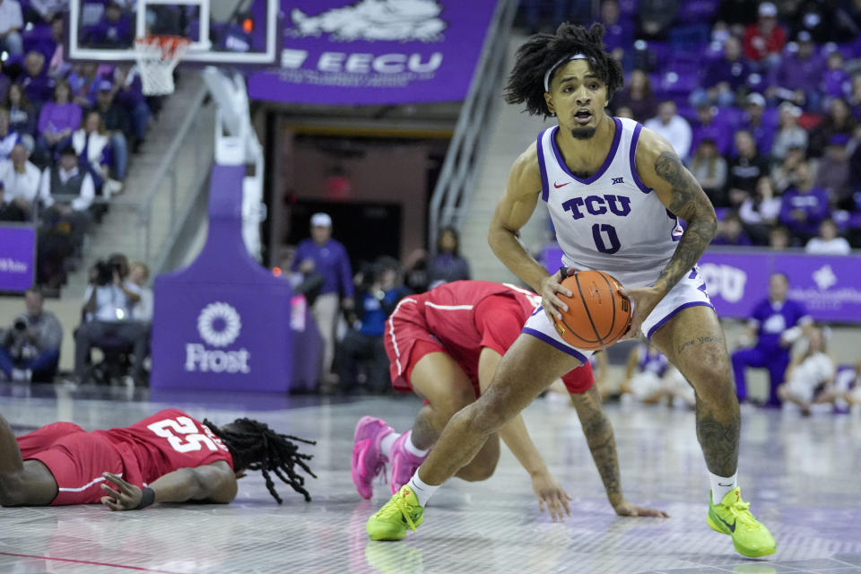 TCU guard Micah Peavy (0) controls the ball as Houston forward Joseph Tugler (25) and guard Ramon Walker Jr. fall to the floor while defending during the first half of an NCAA college basketball game, Saturday, Jan. 13, 2024, in Fort Worth, Texas. (AP Photo/Julio Cortez)