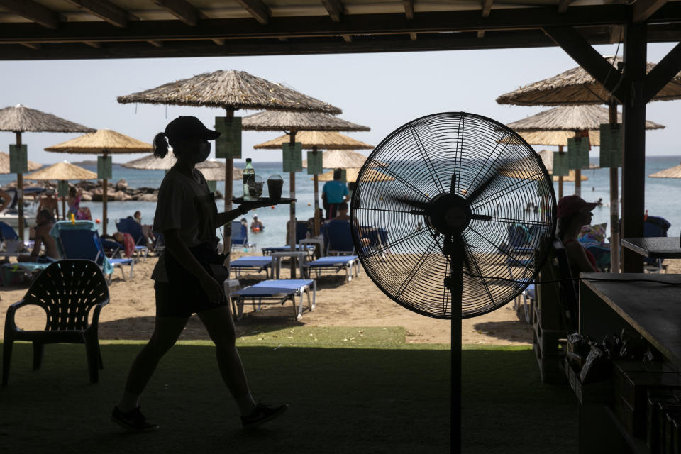 A waitress serves refreshments at a beach bar of Lagonissi village, a few miles southwest of Athens, on Thursday, July 29, 2021. One of the most severe heat waves recorded since 1980s scorched southeast Europe on Thursday, sending residents flocking to the coast, public fountains and air-conditioned locations to find some relief, with temperatures rose above 40 C (104 F) in parts of Greece and across much of the region. (AP Photo/Yorgos Karahalis)