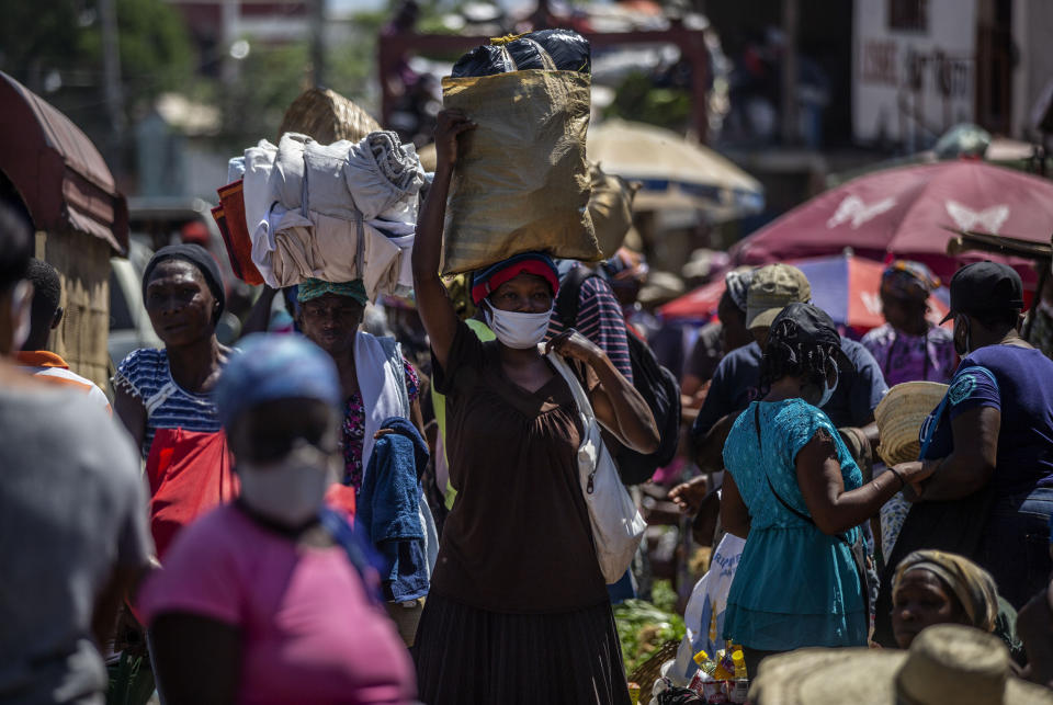 Customers wearing protective face masks as a precaution against the spread of the new coronavirus, walk through a street market in Port-au-Prince, Haiti, Saturday, June 5, 2021. Haiti defied predictions and perplexed health officials by avoiding a COVID-19 crisis for more than a year, but the country of more than 11 million people that has not received a single vaccine is now battling a spike in cases and deaths. (AP Photo/Joseph Odelyn)