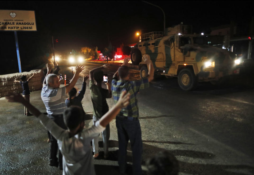 Local residents jeer and applaud as a convoy of Turkish forces vehicles and trucks carrying tanks and armoured personnel carriers is driven in Sanliurfa province, southeastern Turkey, Tuesday, Oct. 8, 2019. The Turkey - Syria border has became a hot spot as Turkish Vice President Fuat Oktay said Turkey was intent on combatting the threat of Syrian Kurdish fighters across its border in Syria.(AP Photo/Lefteris Pitarakis)