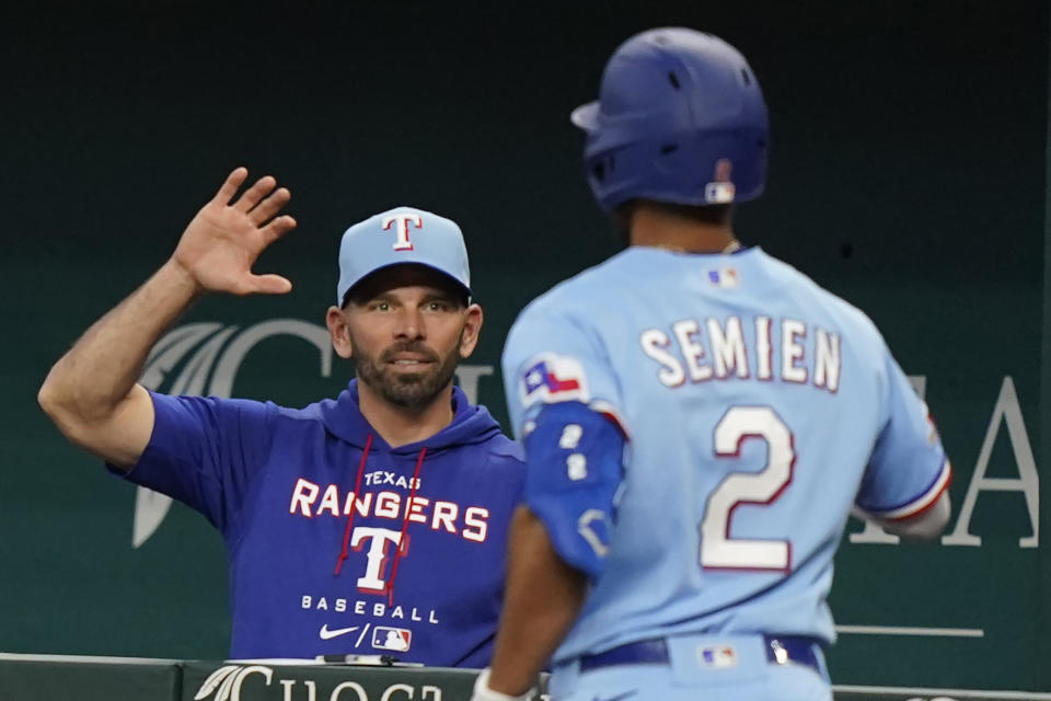Texas Rangers manager Chris Woodward, left, congratulates Marcus Semien (2) after Semien hit a solo home run during third inning of a baseball game against the Seattle Mariners in Arlington, Texas, Sunday, June 5, 2022. (AP Photo/LM Otero)