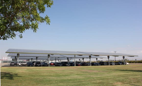 Solar carport with cars under it on a sunny day.