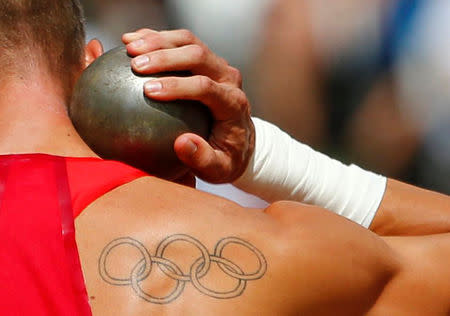 A tattoo of the Olympic rings is seen on the back of Trey Hardee of the U.S. as he competes in the men's decathlon shot put event at the London 2012 Olympic Games at the Olympic Stadium August 8, 2012. REUTERS/Kai Pfaffenbach/File Photo