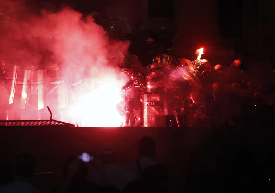 Protesters clash with riot police on the steps of the Serbian parliament during a protest in Belgrade, Serbia, Friday, July 10 2020. Hundreds of demonstrators tried to storm Serbia's parliament on Friday, clashing with police who fired tear gas during the fourth night of protests against the president's increasingly authoritarian rule. The protests started on Tuesday when President Aleksandar Vucic announced that Belgrade would be placed under a new three-day lockdown following a second wave of confirmed coronavirus infections. (AP Photo/Darko Vojinovic)