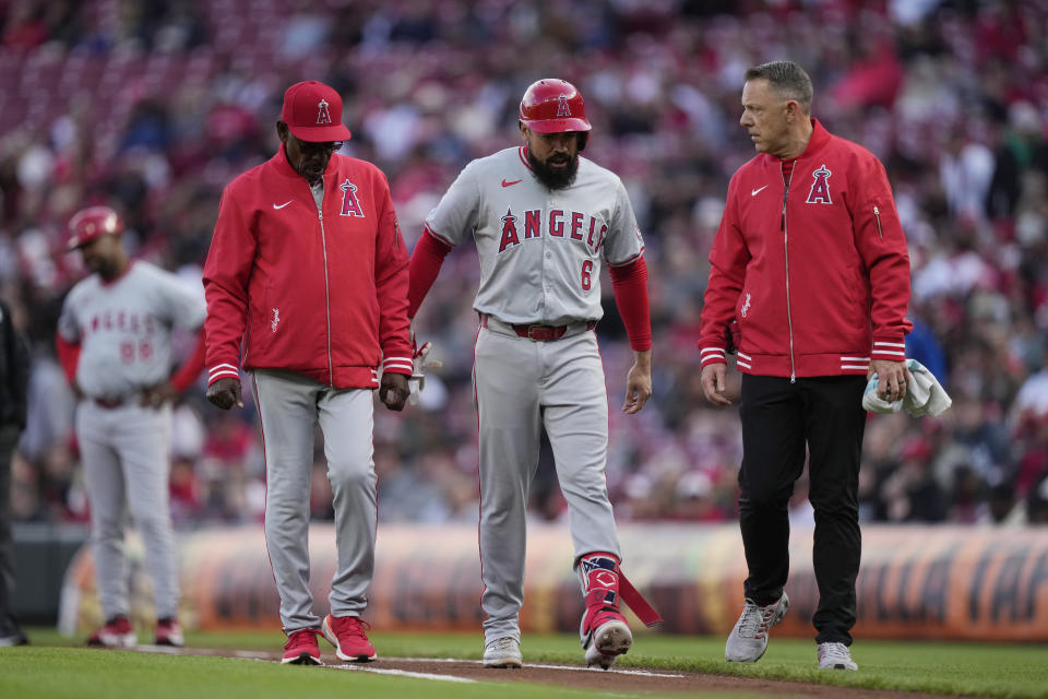 Los Angeles Angels Anthony Rendon (6) walks from the field with Los Angeles Angels manager Ron Washington, left, after hitting a single in the first inning of a baseball game against the Cincinnati Reds on Saturday, April 20, 2024, in Cincinnati. Rendon left the game after the play due to an injured ankle. (AP Photo/Carolyn Kaster)