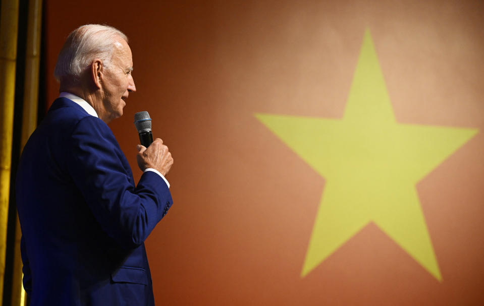 Joe Biden holding microphone in front of Vietnam's flag.  (Saul Loeb / AFP via Getty Images)