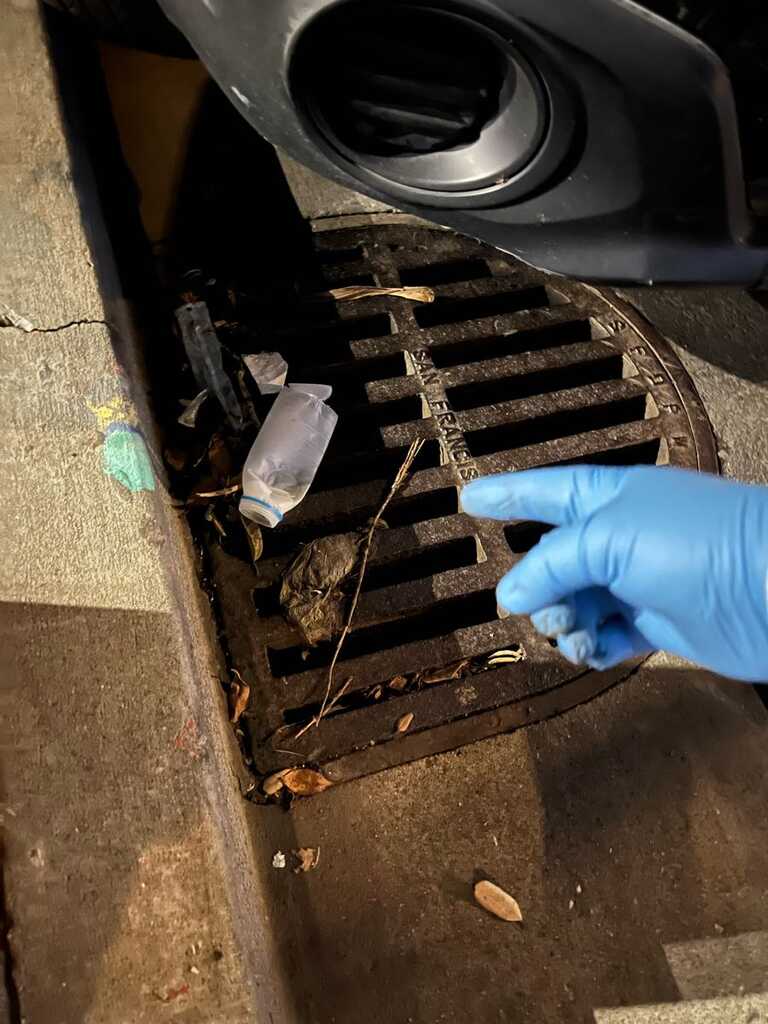 gloved hang points at plastic bottle garbage covering storm drains