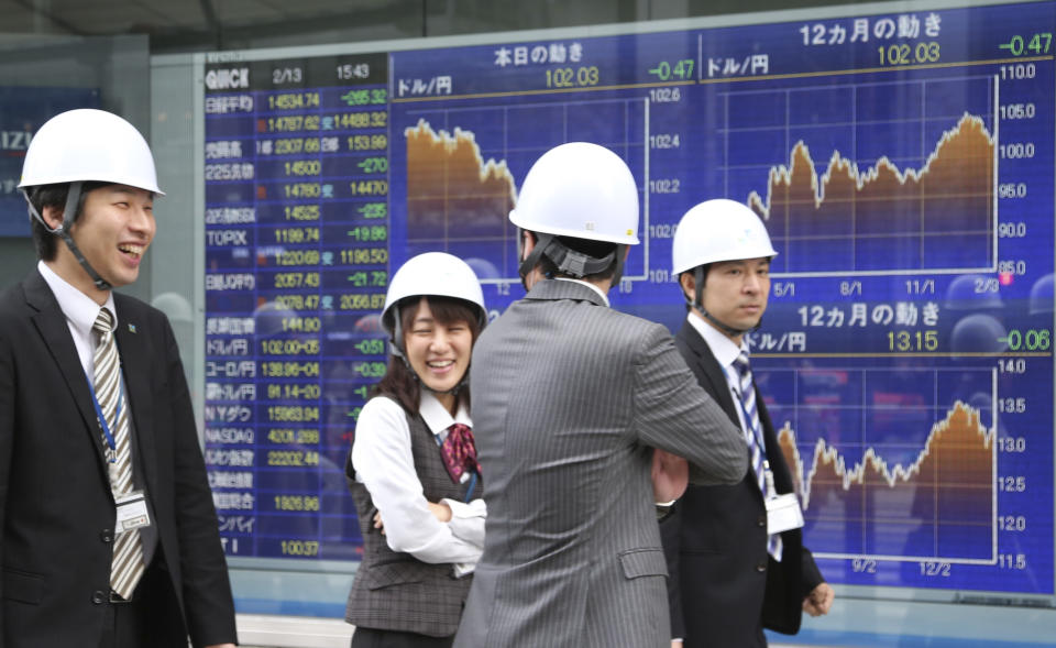 Office workers wearing helmets walk by an electronic stock board of a securities firm during their disaster drill in Tokyo Thursday, Feb. 13, 2014. Asian stocks were mostly lower Thursday, led by a fall in Tokyo after Wall Street ended lower for the first time this week. Japan's Nikkei 225, the region's main index, dropped 265.32 points, or 1.79 percent to 14,534.74. (AP Photo/Koji Sasahara)