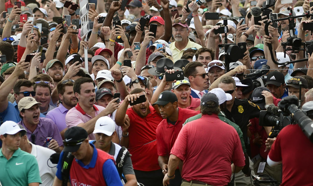 File-This Sept. 23, 2018, file photo shows Tiger Woods, lower center, and Rory McIlroy, lower left, emerging from a horde of fans following Tiger on their way to the 18th green during the final round of the Tour Championship golf tournament in Atlanta. Woods says he got chills watching the highlights because of all the energy in the crowd. (AP Photo/John Amis, File)