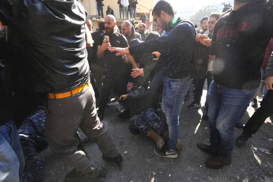 Anti-government protesters beat a riot policeman during scuffle with riot police outside the ministry of Justice, in Beirut, Lebanon, Thursday, Jan. 26, 2023. Scores of protesters Thursday scuffled with riot police as they tried to break into the Beirut Justice Palace, rejecting an order from Lebanon's judiciary that further crippled the probe into a massive port explosion over two years ago. (AP Photo/Hassan Ammar)