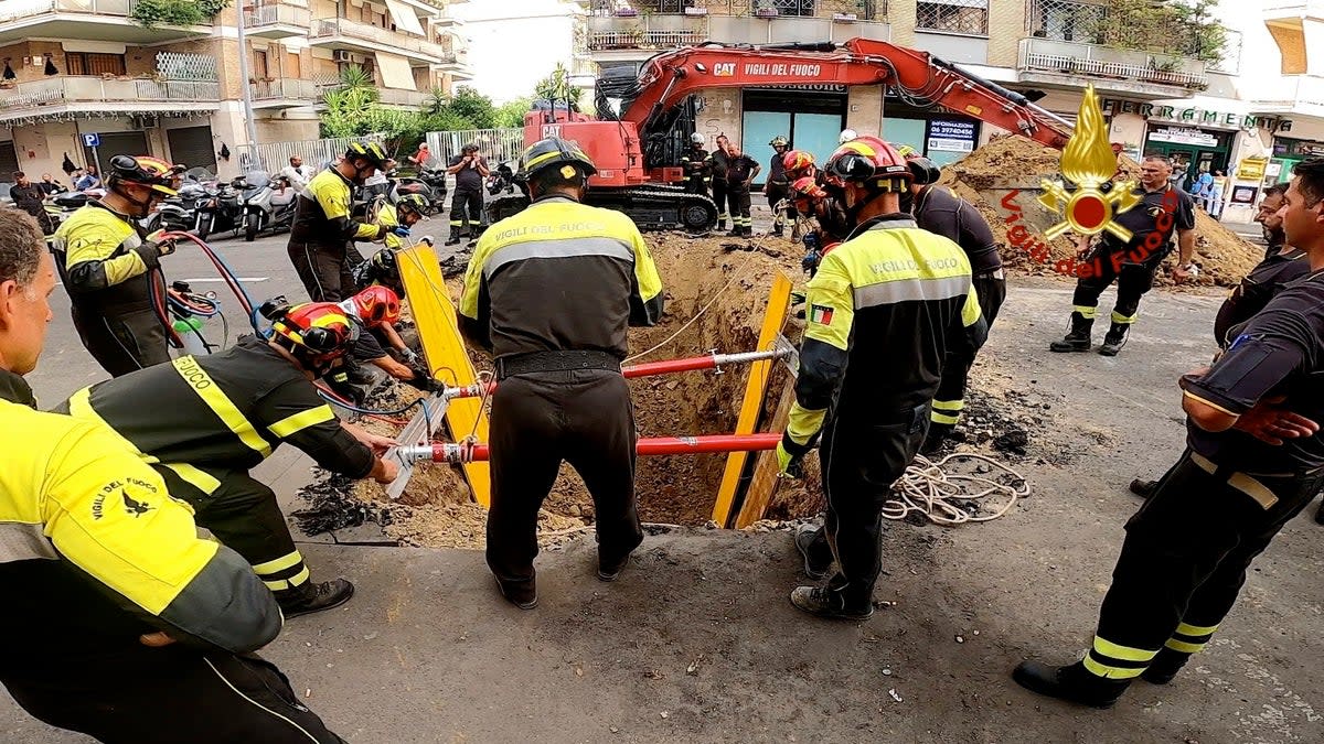 Italian firefighters dig up the road to rescue a man blocked in the tunnel (AP)